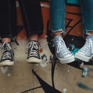 person in blue denim jeans wearing black and white converse all star high top sneakers