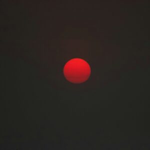 The red sun shines dimly in a dark sky.